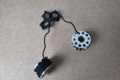 Angefangene Occhispitze. Die Fadenenden sind auf Nähmaschinenspulen gewickelt.