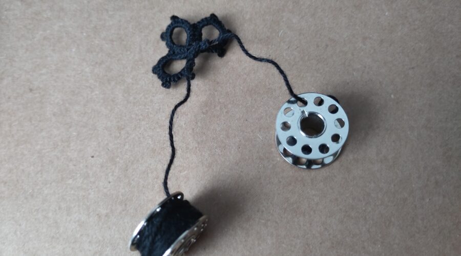 Angefangene Occhispitze. Die Fadenenden sind auf Nähmaschinenspulen gewickelt.