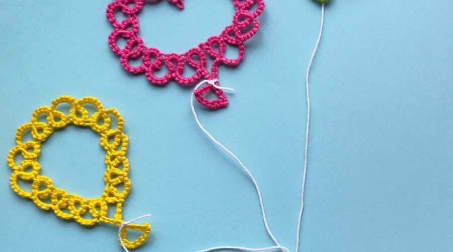 Drei Luftballons, die in Occhitechnik erstellt wurden vor blauem Hintegrund. Eine Hand hält alle drei Ballons an ihren Schnüren