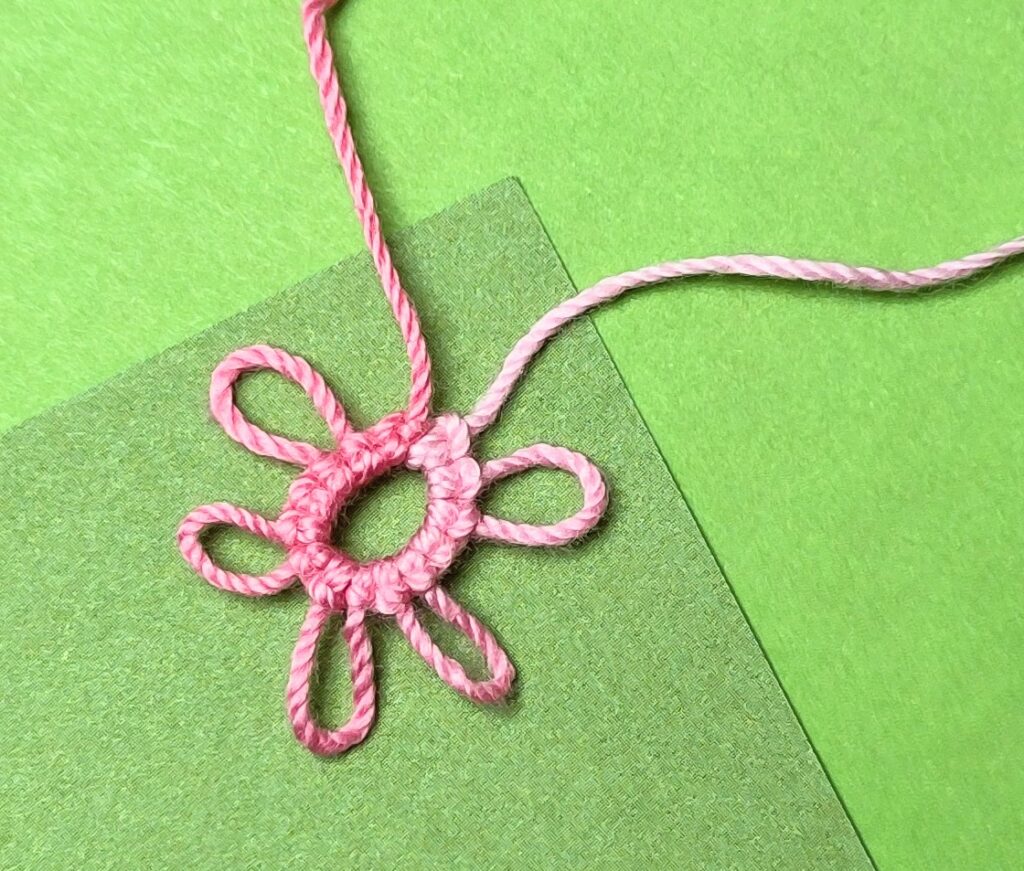 Ein rosa Occhiringe auf grünem Hintergrund mit mehreren Picots