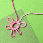 Ein rosa Occhiringe auf grünem Hintergrund mit mehreren Picots