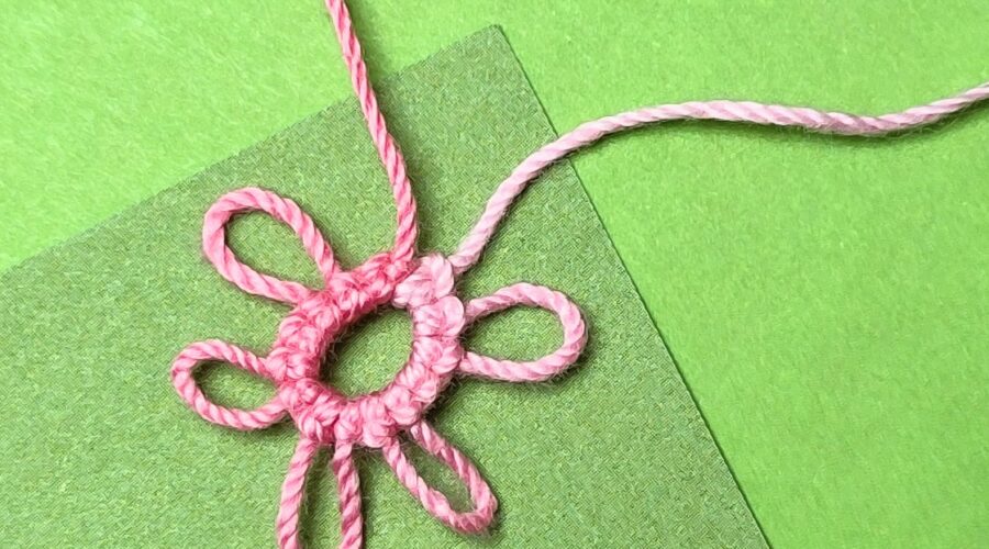 Ein rosa Occhiringe auf grünem Hintergrund mit mehreren Picots