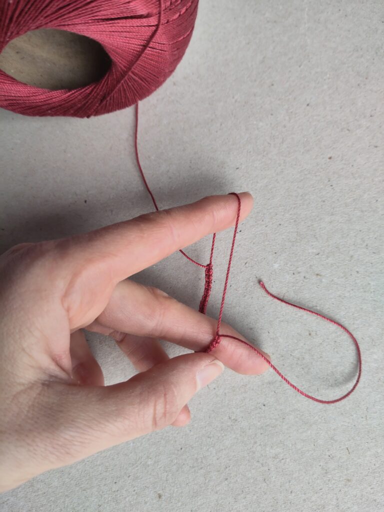 Eine Hand die einen angefangenen Occhiring hält.