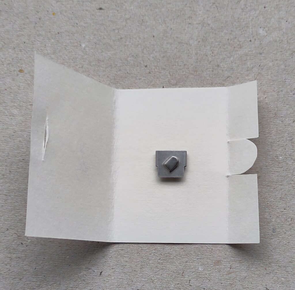 Ein kleiner Fadenschneider in einem Mäppchen auf Pappe