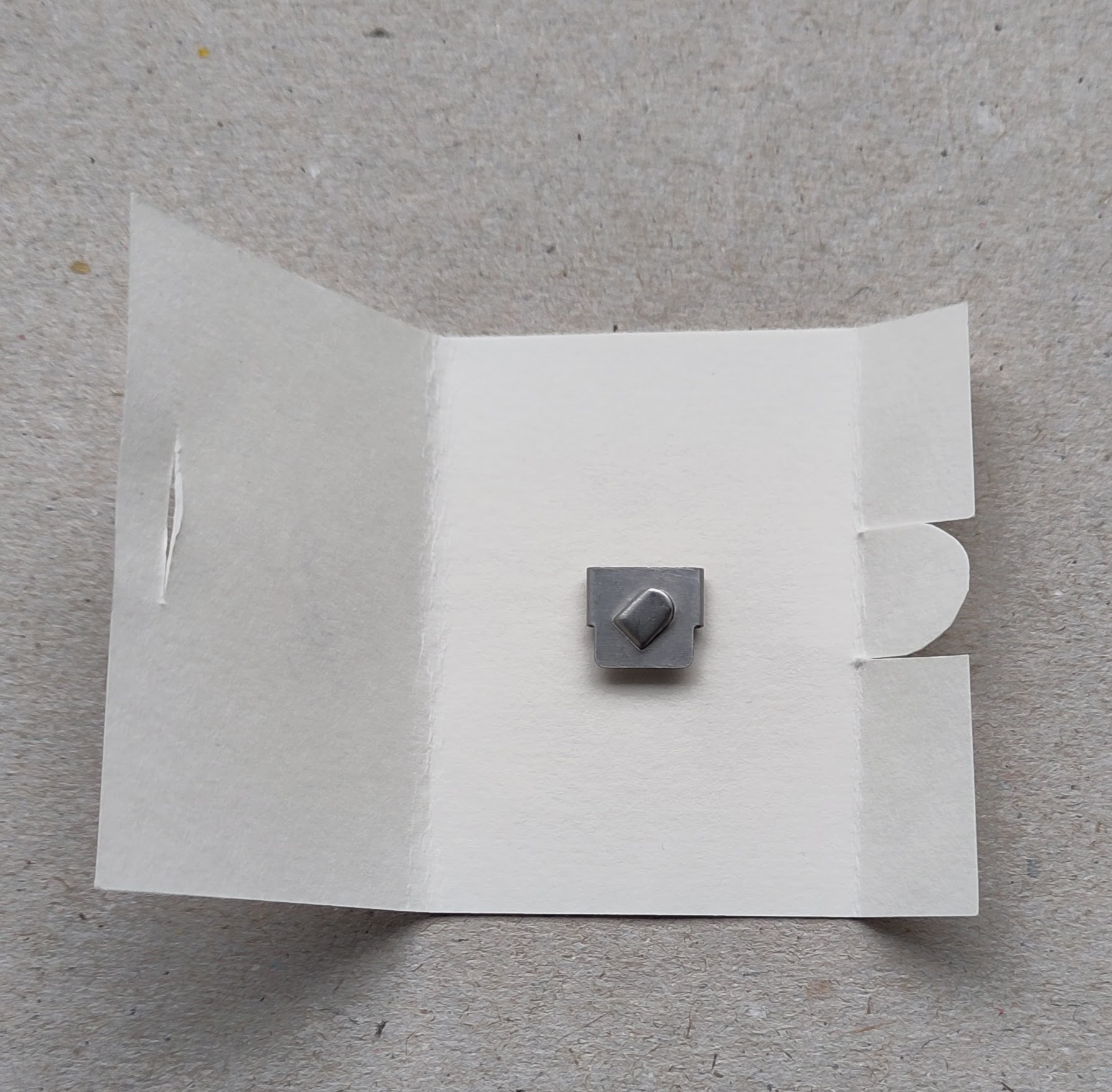 Ein kleiner Fadenschneider in einem Mäppchen auf Pappe