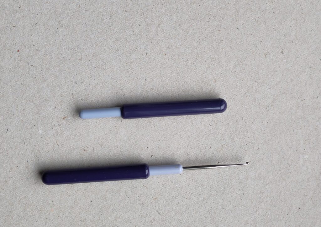 Zwei mal die gleiche Häkelnadel. Einmal geöffnet, einmal geschlossen. Die ABdeckung dient in geöffnetem Zusatend als Griff