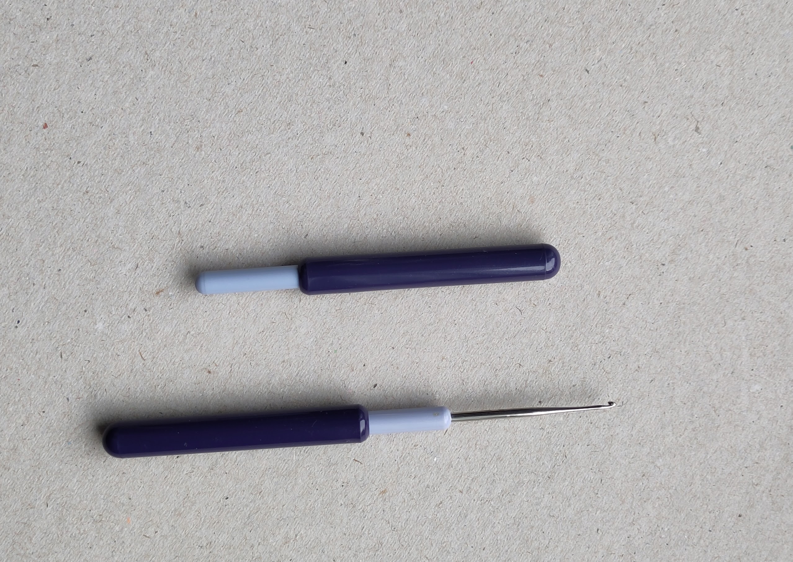 Zwei mal die gleiche Häkelnadel. Einmal geöffnet, einmal geschlossen. Die ABdeckung dient in geöffnetem Zusatend als Griff