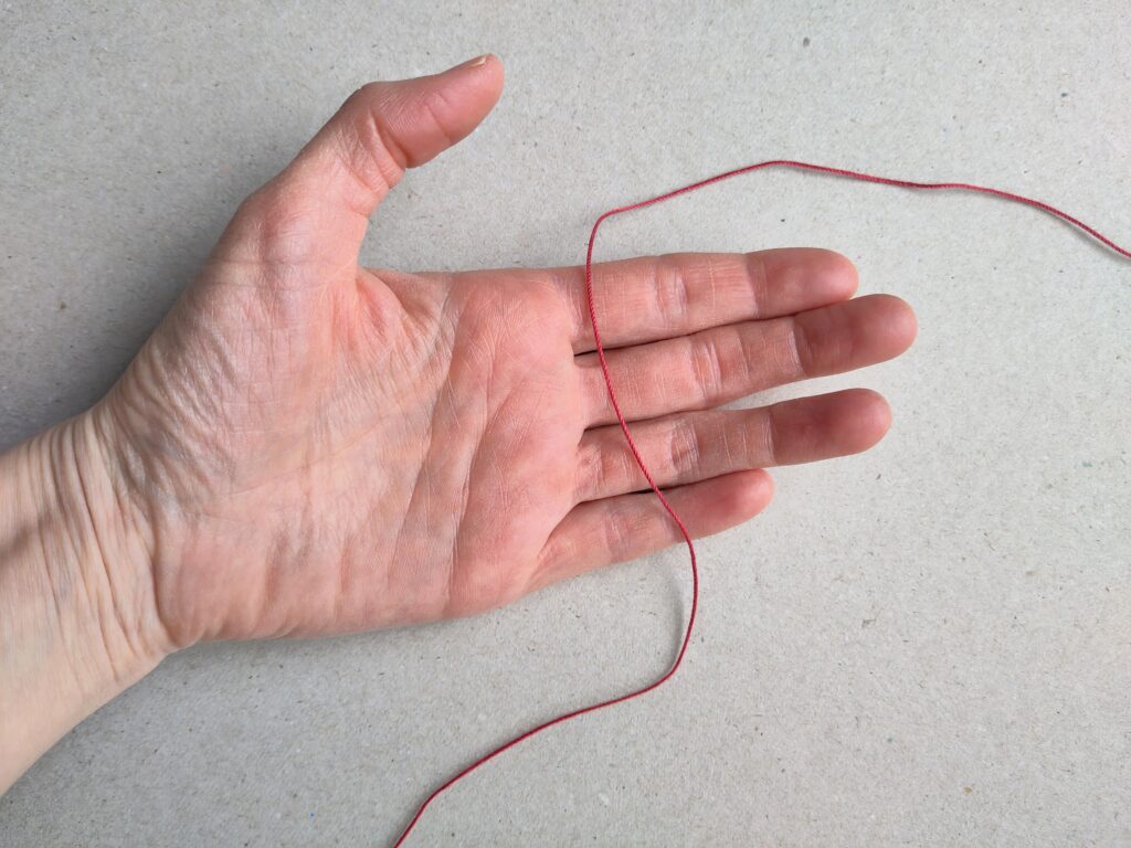 eine ausgestreckte Hand mit einem Faden