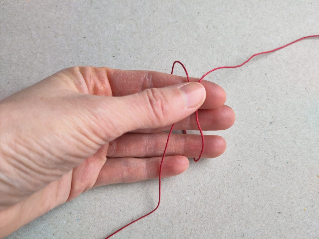 Eine Hand, die eine Öse hält um mit einem Occhiring zu starten