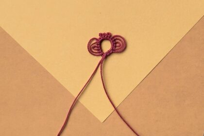 Ein roter Occhiring auf gelbem Grund mit zwei Tripelpicots und drei einfachen Picots