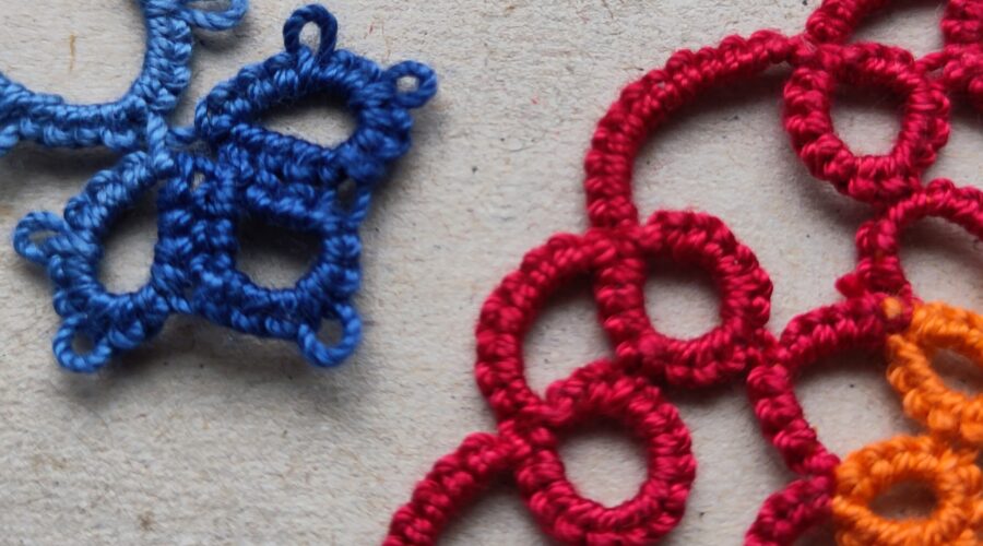 Ein blaues und ein rotes Stück Occhi-Spitze liegen sich gegenüber.