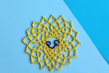 Eine lächelnde gelbe Sonne in Occhitechnik geknotet.