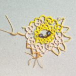 Teststück einer Sonne in Occhitechnik mit verschiedenafrbigen Garnen und unterschiedlich gearbeiteten Sonnenstrahlen.