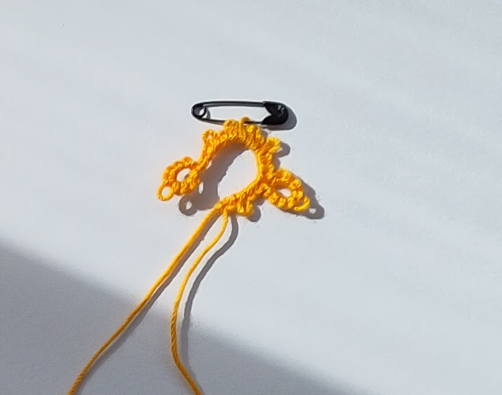 Eine Angefangene Occhiarebit mit einer Minisicherheitsnadel als Maschenmarkierer an einem Picot